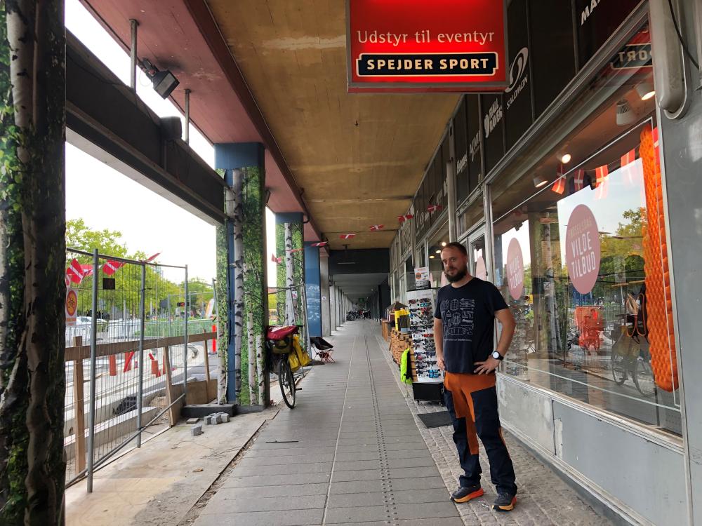 Daniel Miller er butikschef i Spejder Sport på Jernbanepladsen 55. Der er få meter mellem butiksdøren og den kommende letbanestation, der etableres lige bag byggehegnet som ses i venstre side af billedet).